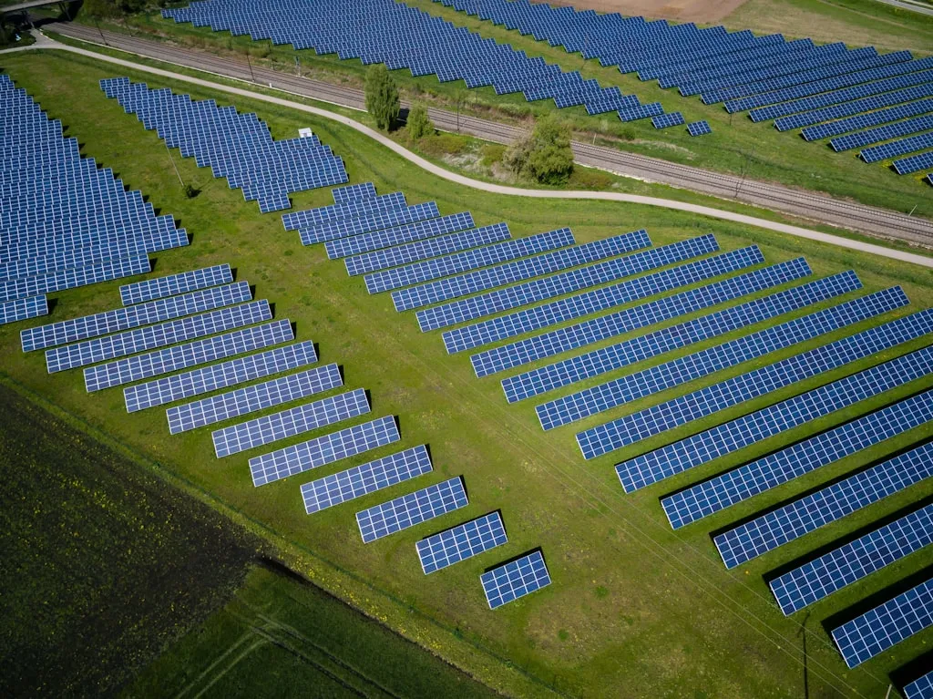 太陽光パネルが並ぶ広大なソーラーファームと風力発電設備の複合再エネ施設