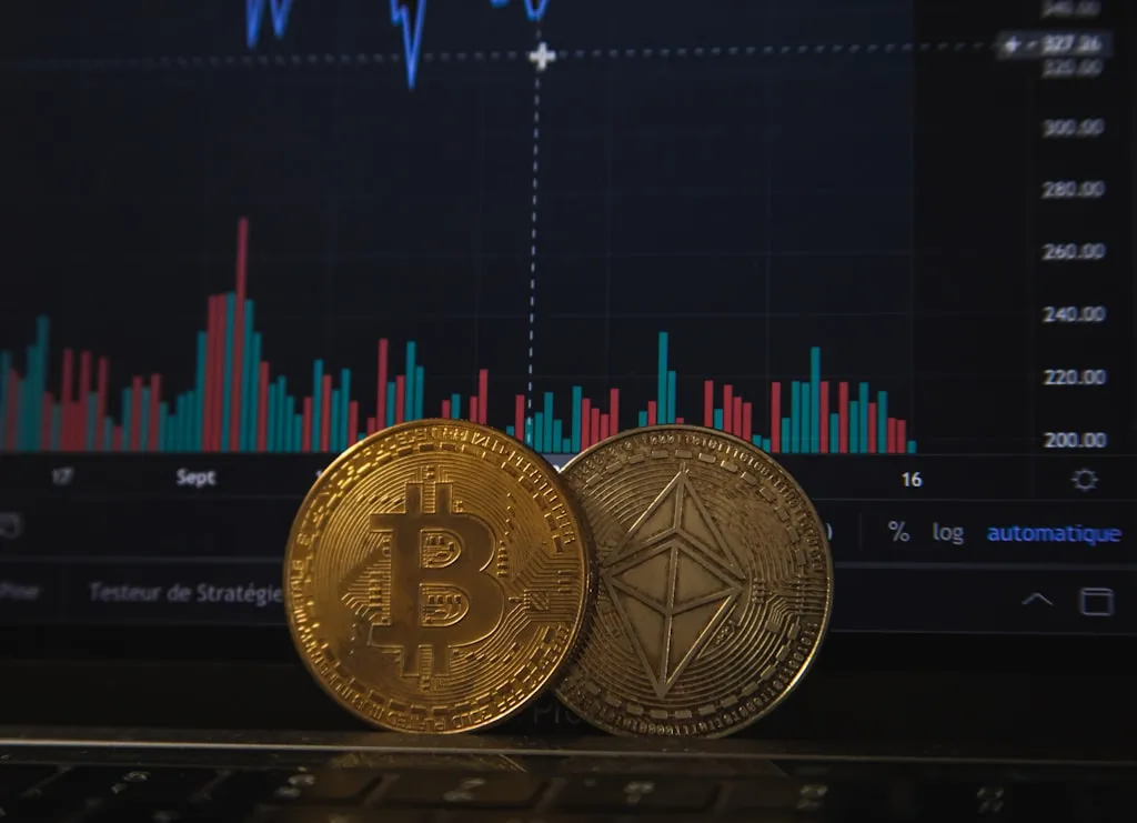 物理的なビットコインの硬貨と背景のグラフチャートが並ぶ暗号資産イメージ