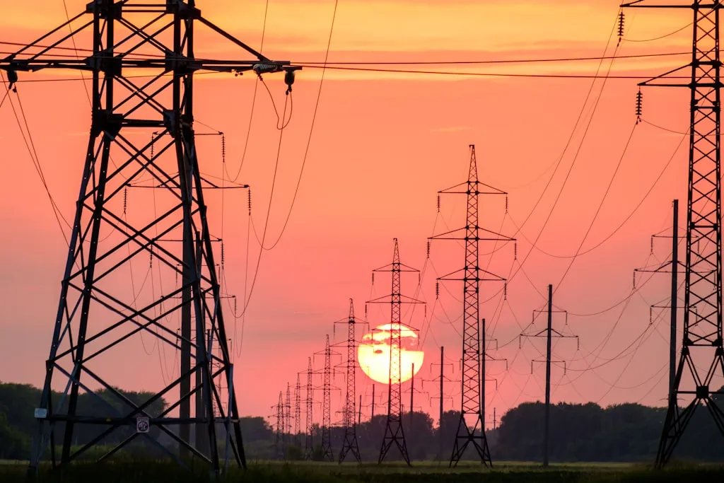 夕暮れ空を背景にシルエットで浮かぶ高圧送電線の鉄塔群