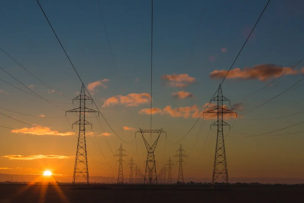 夕暮れ時の空を背景にそびえ立つ送電鉄塔群、エネルギーインフラの幾何学的構造