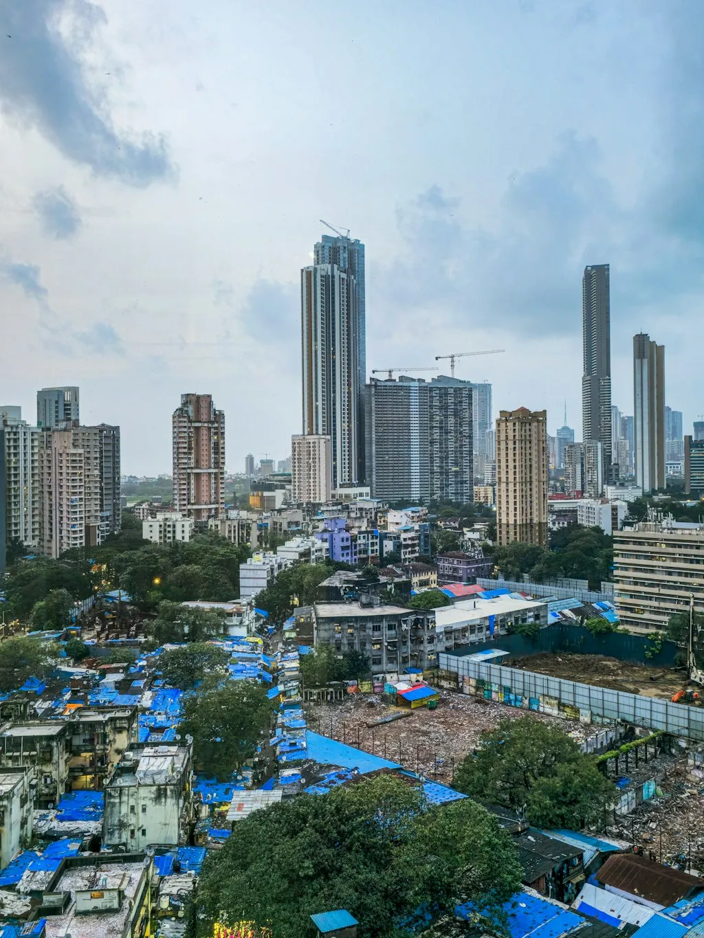 ムンバイの旧来の低層住宅地を背景に林立する近代的な高層ビルと住宅棟が示す都市開発の対比
